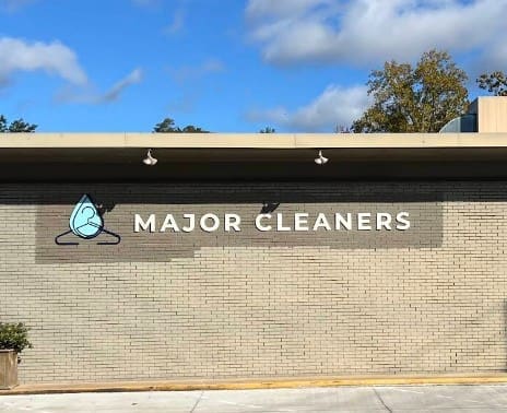 The exterior of a building with a sign that reads "MAJOR CLEANERS" next to a logo of a hanger and a water droplet.